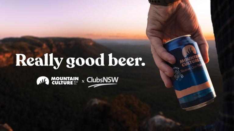 man holding beer in front of mountains